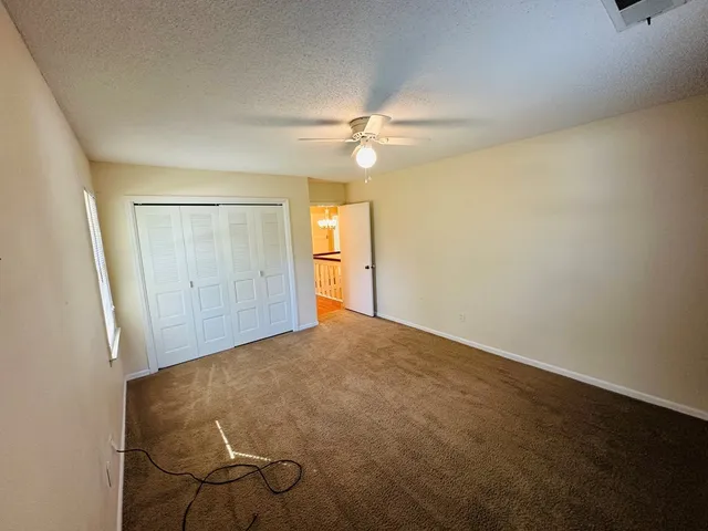 an empty room with a ceiling fan and carpet
