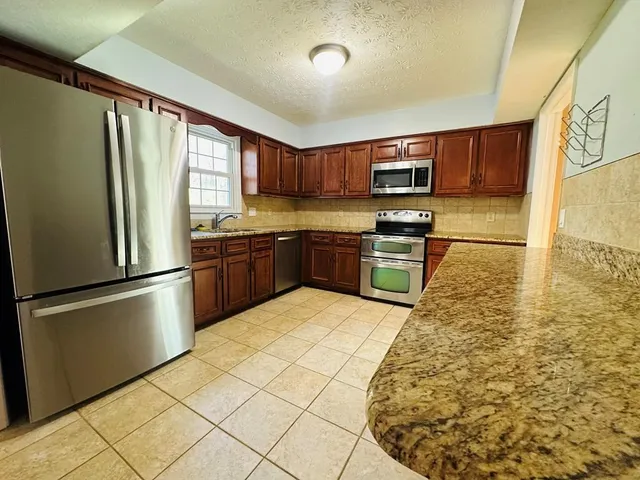 a kitchen with stainless steel appliances granite countertop a refrigerator sink and stove