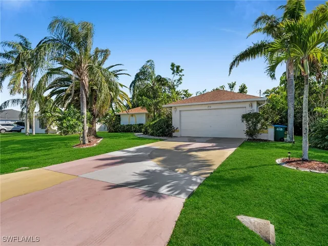 a view of a house with a yard and palm trees