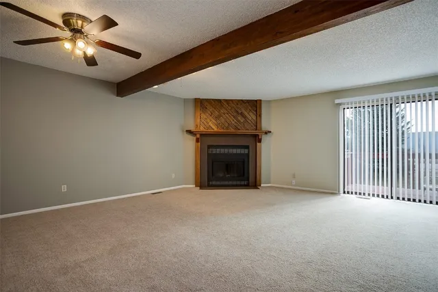 an empty room with windows fireplace and fan