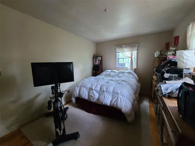 a bedroom with a bed and a flat tv screen on the dresser