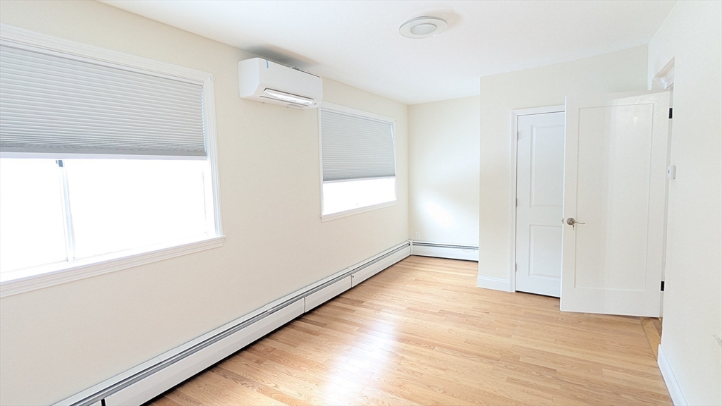 446 Lowell Avenue, Unit 446 Newton, MA 02460 - Photo 5 of 15 a view of an empty room with wooden floor and a window
