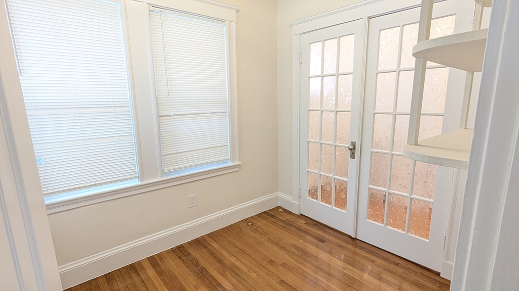 446 Lowell Avenue, Unit 446 Newton, MA 02460 - Photo 8 of 15 a view of an empty room with wooden floor and a window