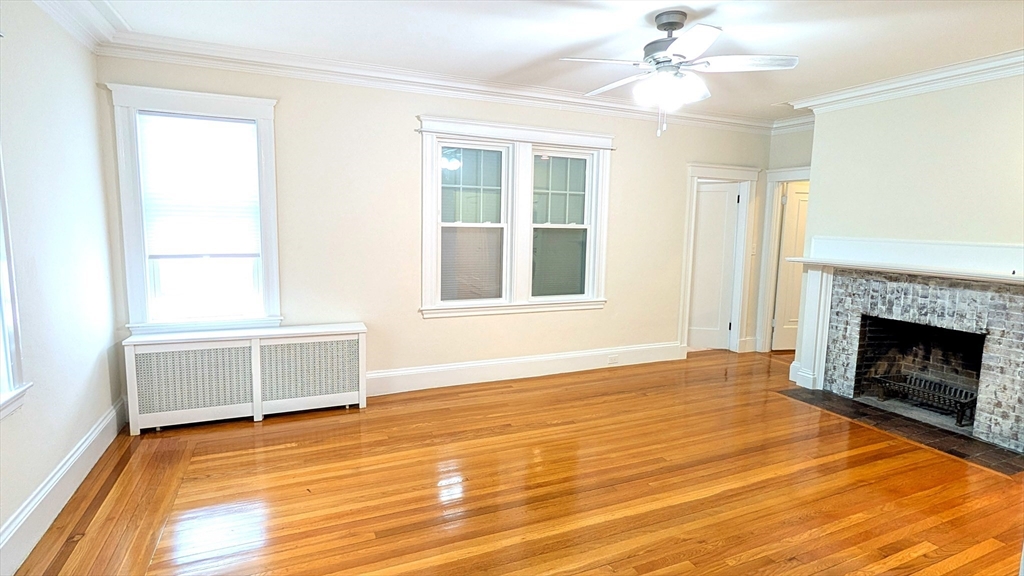 446 Lowell Avenue, Unit 446 Newton, MA 02460 - Photo 9 of 15 an empty room with wooden floor fireplace and windows