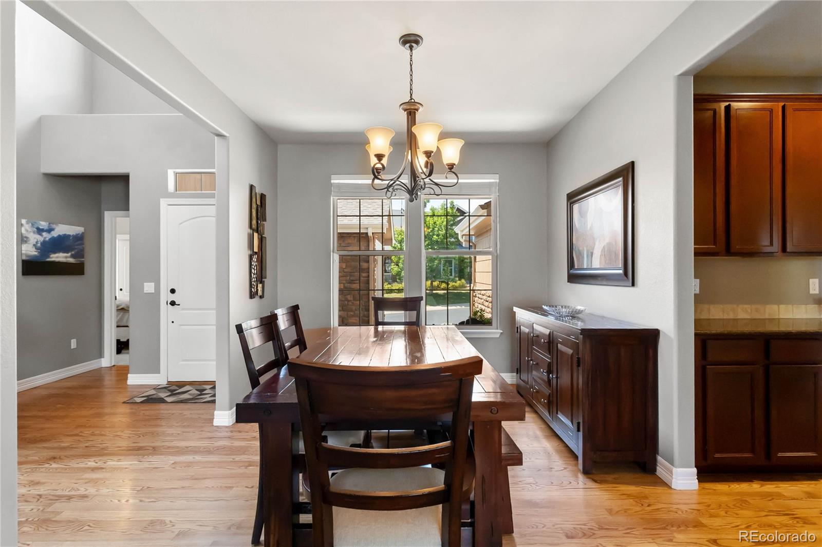 3034 Mashie Circle Castle Rock, CO 80109 - Photo 13 of 50 a dining room with wooden floor a chandelier a wooden table and chairs