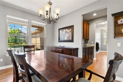 a dining room with wooden floor a chandelier a wooden table and chairs