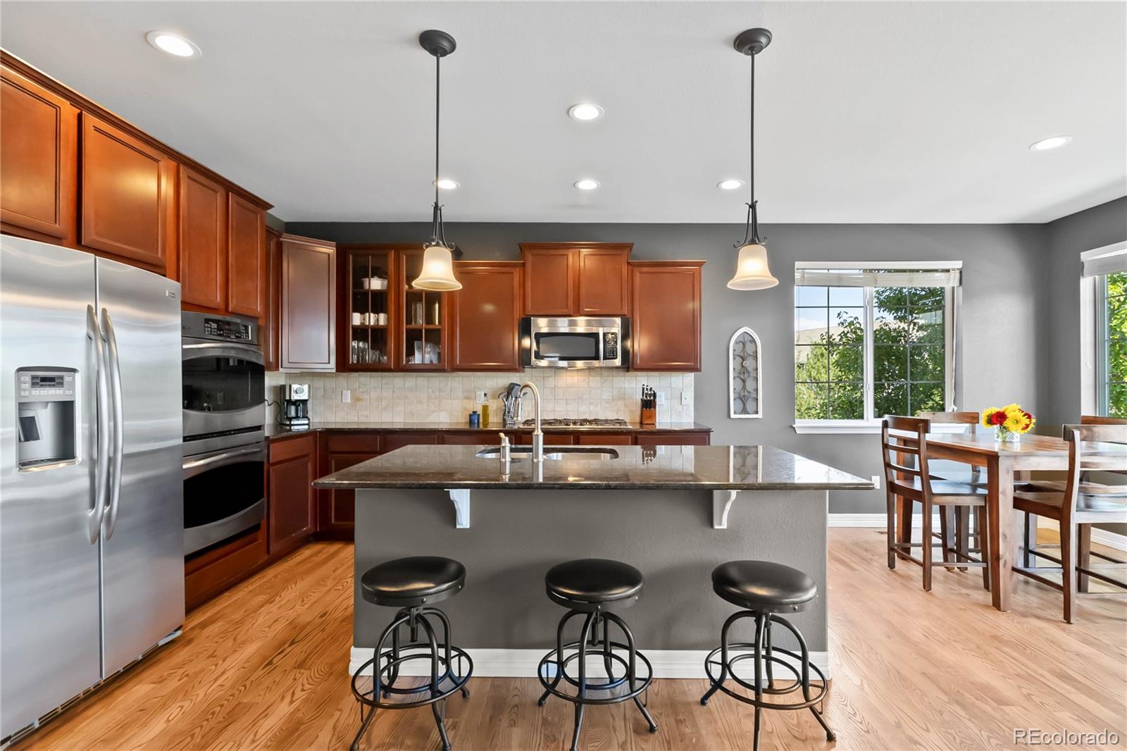 3034 Mashie Circle Castle Rock, CO 80109 - Photo 8 of 50 a kitchen with stainless steel appliances granite countertop a stove top oven a refrigerator a sink and chairs