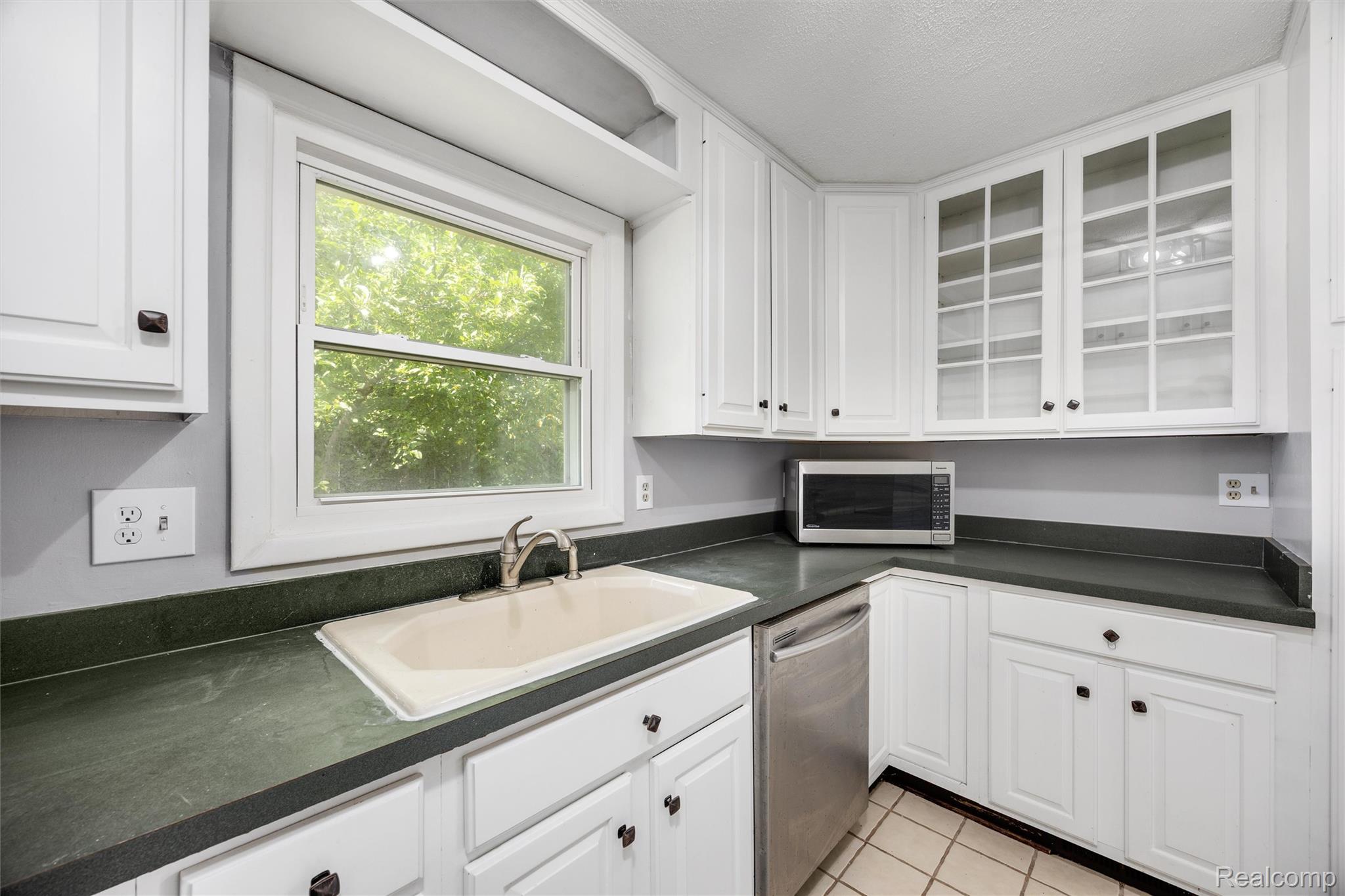 4942 Butler Drive Troy, MI 48085 - Photo 9 of 33 Kitchen featuring white cabinetry, dark countertops, a built-in sink, and a window above the sink