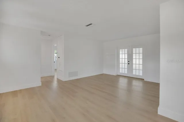 a view of an empty room with a window and wooden floor
