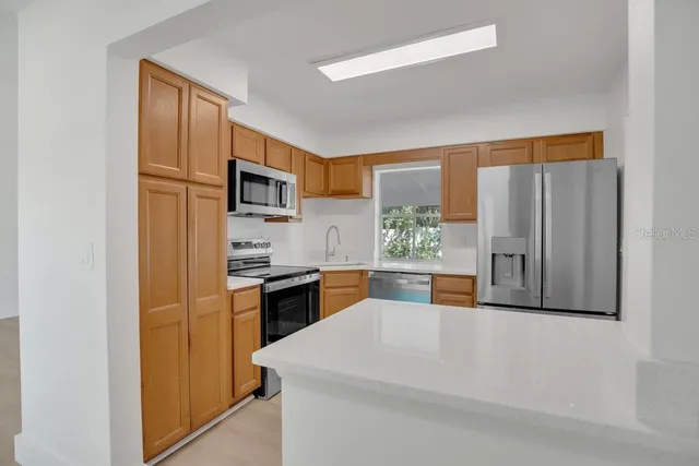 a large kitchen with cabinets stainless steel appliances and a window