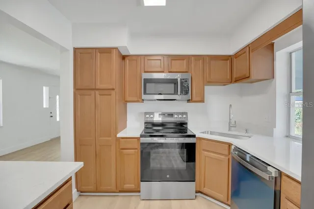 a kitchen with granite countertop a sink stove and microwave