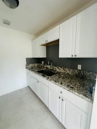 a kitchen with granite countertop a sink a stove and cabinets
