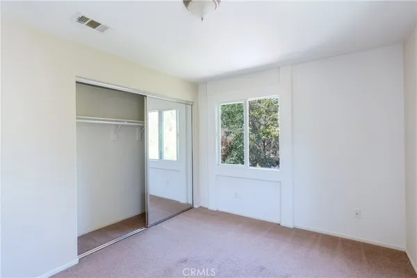 an empty room with wooden floor fireplace and windows