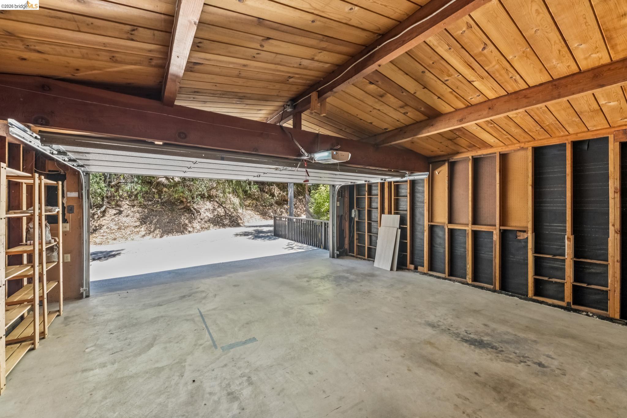 6645 Heather Ridge Way Oakland, CA 94611 - Photo 54 of 61 Spacious garage with exposed wood beam ceiling, concrete flooring, and an automatic garage door opener