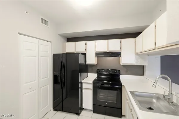 a kitchen with a sink a refrigerator and cabinets
