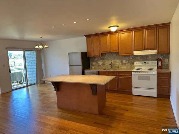 a kitchen with kitchen island a sink wooden floor and stainless steel appliances