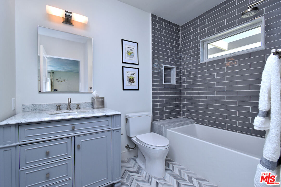 922 Berkeley Street Santa Monica, CA 90403 - Photo 15 of 33 a bathroom with a granite countertop toilet a sink a mirror and bathtub