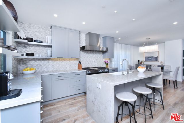 a kitchen with stainless steel appliances granite countertop a sink a stove a refrigerator and a dining table with wooden floor