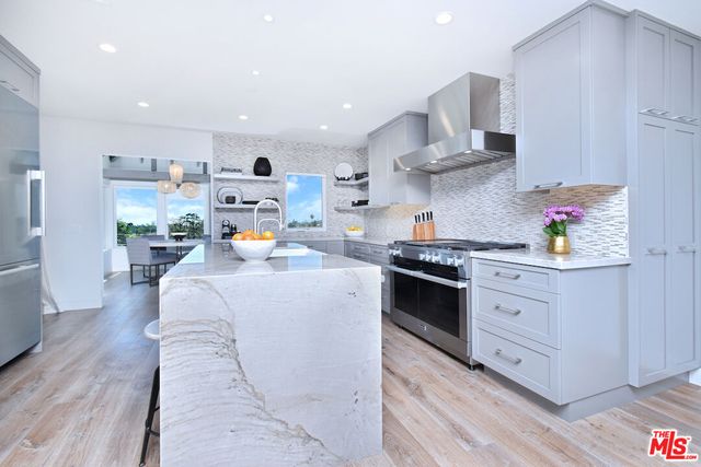 a kitchen with stainless steel appliances granite countertop a sink a stove and a wooden floors