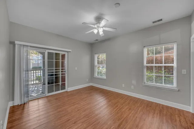 an empty room with wooden floor and windows