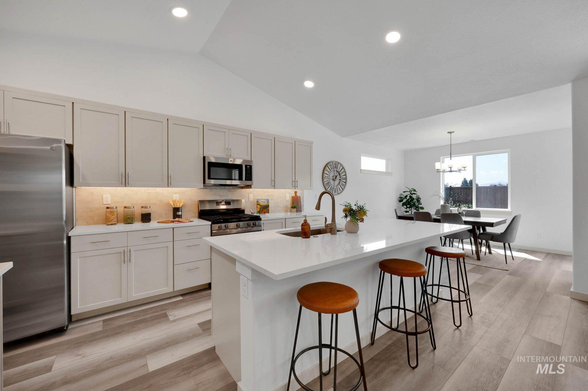3305 East Fitz Roy Street Kuna, ID 83634 - Photo 3 of 23 Kitchen with backsplash, stainless steel appliances, vaulted ceiling, a kitchen breakfast bar, and an island with sink