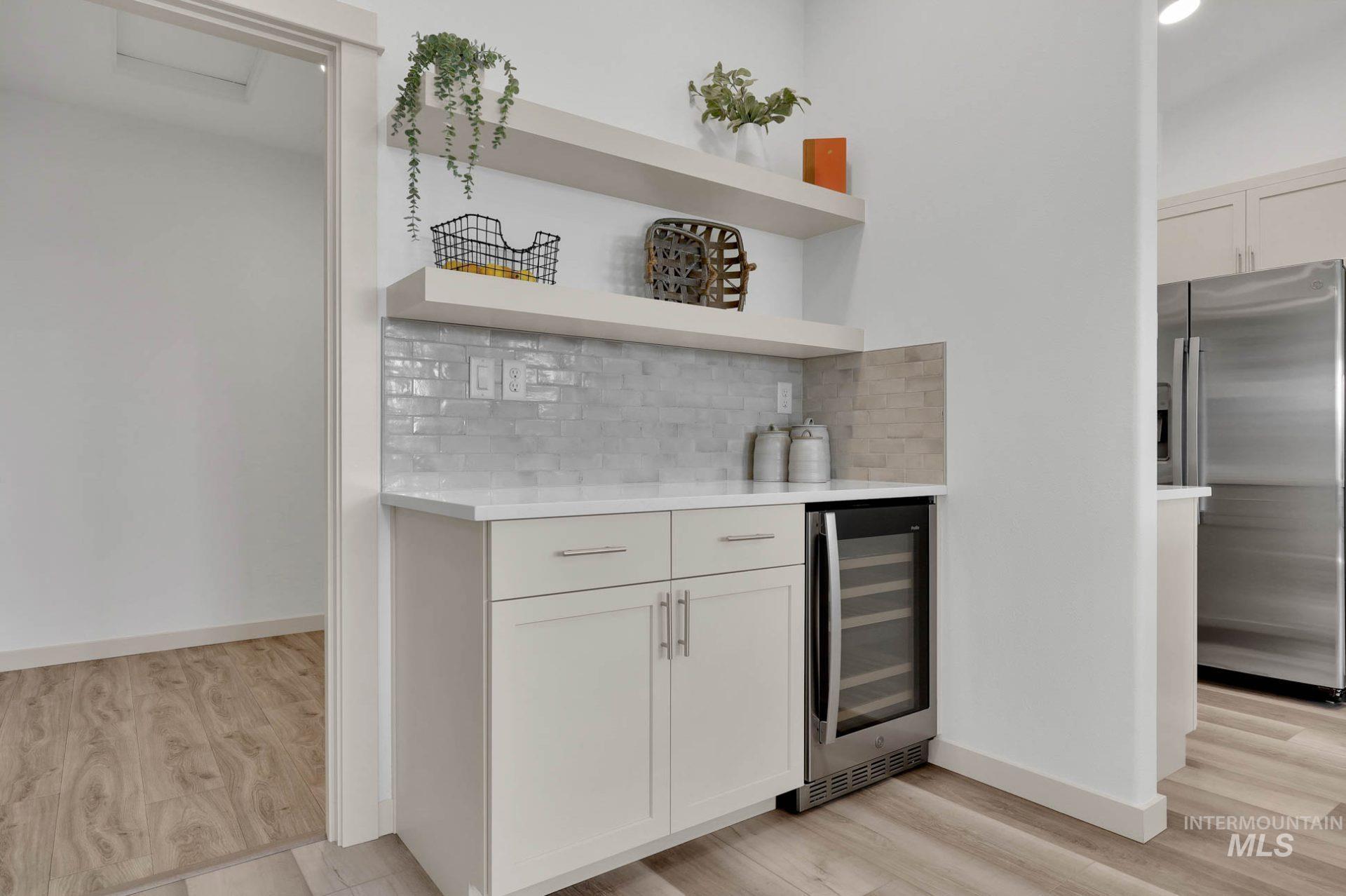 3305 East Fitz Roy Street Kuna, ID 83634 - Photo 9 of 23 Indoor dry bar with stainless steel fridge, light stone countertops, decorative backsplash, open shelves, and wine cooler