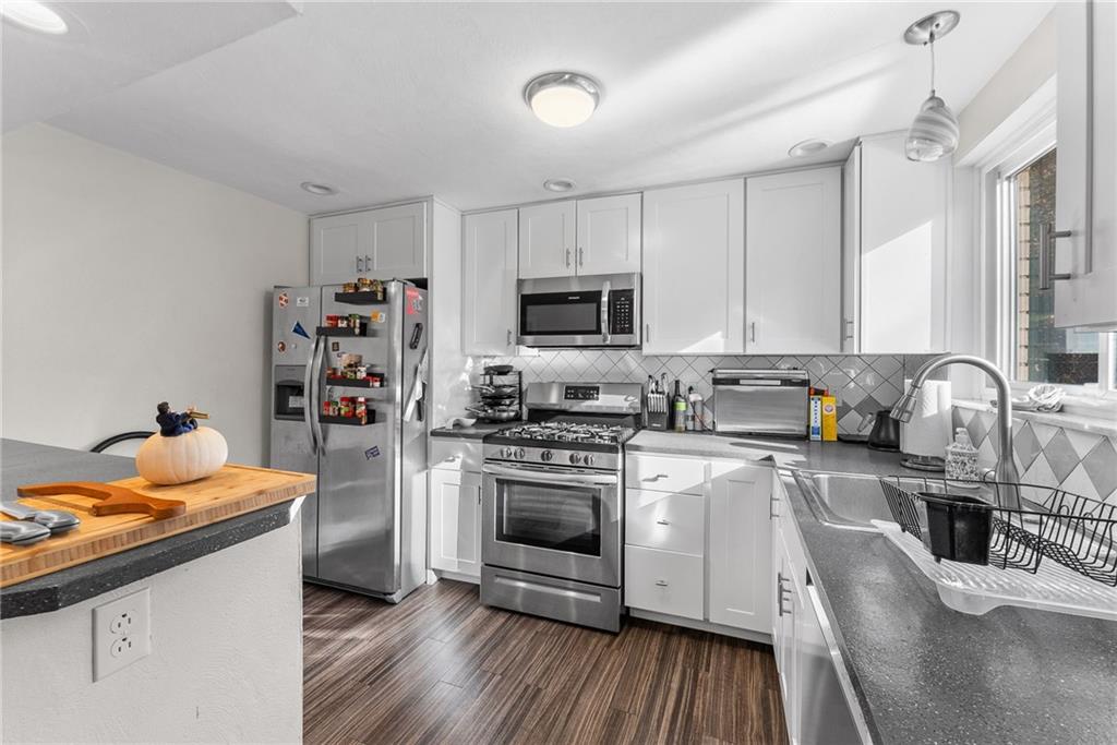 400 Pearce Road Pittsburgh, PA 15234 - Photo 8 of 31 a kitchen with stainless steel appliances granite countertop a stove top oven a sink dishwasher and a refrigerator with wooden floor
