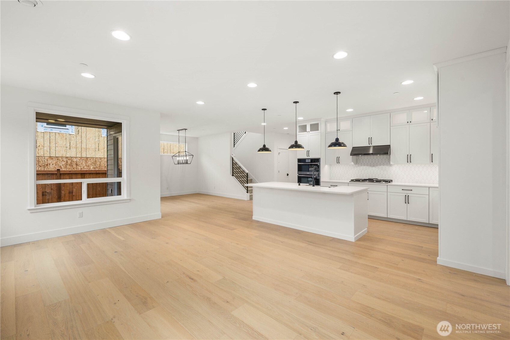722 211th Place Southeast Bothell, WA 98021 - Photo 12 of 27 a large white kitchen with kitchen island a sink wooden floor and a large window