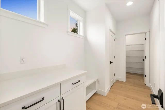 a view of a hallway with wooden floor and a bathroom