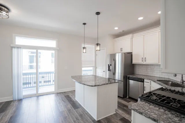 a kitchen with stainless steel appliances granite countertop a refrigerator a stove and a wooden floors