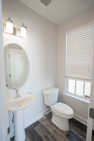 a bathroom with a toilet a sink a mirror and a window