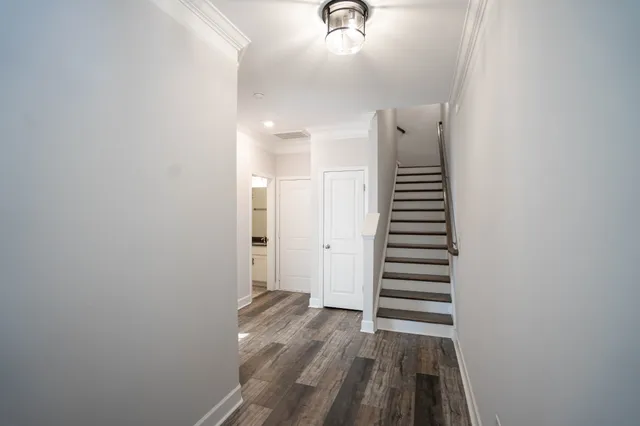 a view of a hallway with stairs and wooden floor