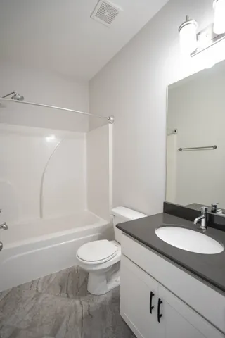 a bathroom with a granite countertop sink toilet a mirror and shower