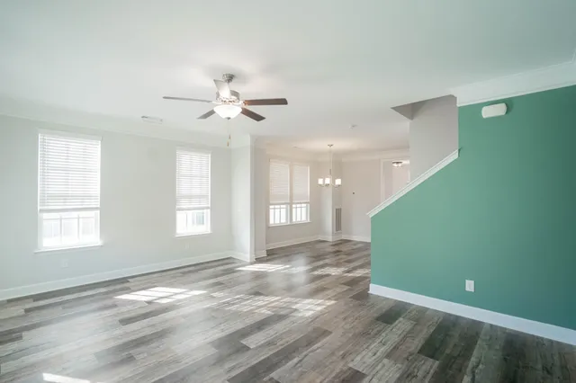 a view of an empty room with window and chandelier fan