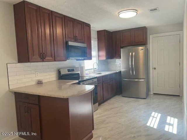 a kitchen with stainless steel appliances granite countertop a refrigerator a sink a stove a washer and dryer