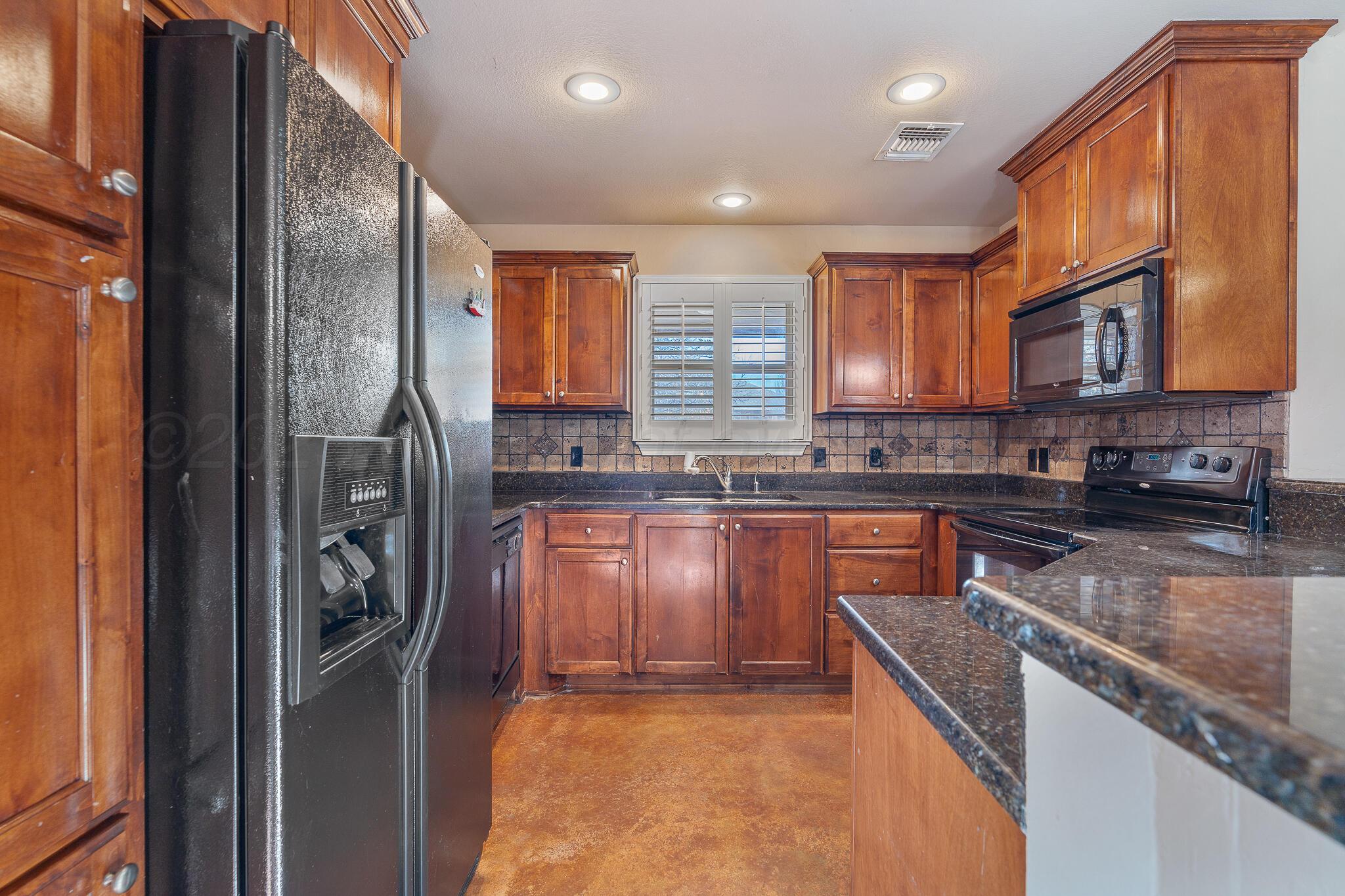 4403 Ross Street Amarillo, TX 79118 - Photo 10 of 27 a kitchen with stainless steel appliances granite countertop a refrigerator a stove and a sink with wooden cabinets