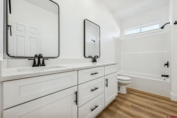 a bathroom with a double vanity sink a toilet and a tub