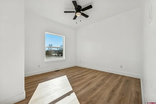 a view of a room with wooden floor and a ceiling fan