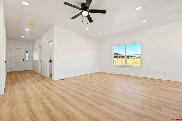 a view of empty room with wooden floor and ceiling fan