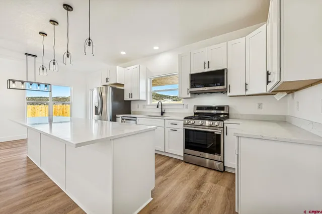 a kitchen with stainless steel appliances kitchen island granite countertop a stove top oven a sink a microwave and a refrigerator