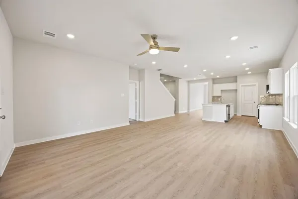 an empty room with wooden floor ceiling fan and window