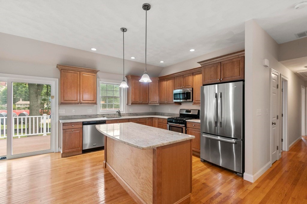 10 Emerald Court Stoneham, MA 02180 - Photo 17 of 42 a kitchen with stainless steel appliances granite countertop a refrigerator a sink dishwasher a kitchen island with wooden floor and large cabinets