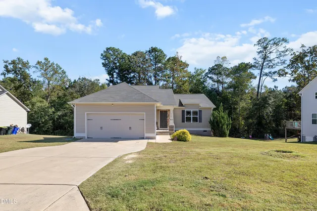 a view of a white house with a yard and large trees