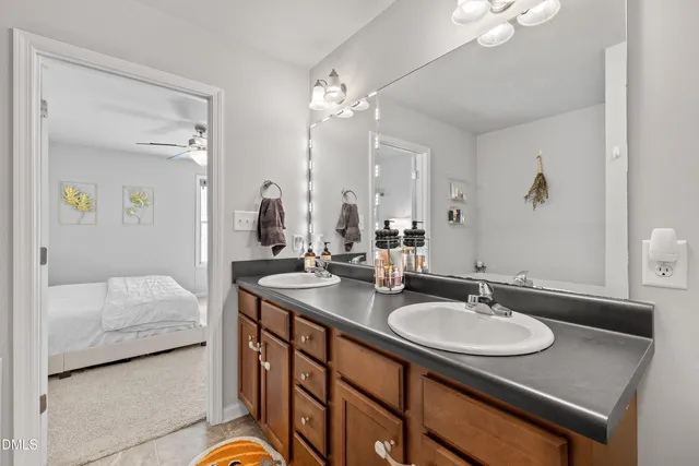 a en suite bathroom with double vanity sinks a vanity a lamp and a mirror