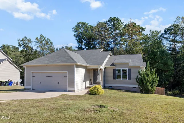 a view of a house with a yard and large tree