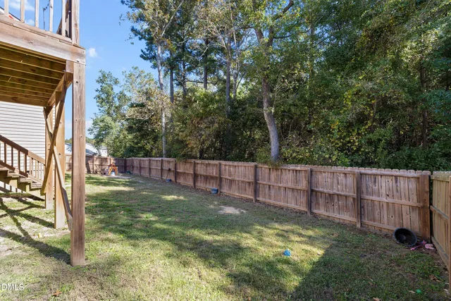 a view of backyard with wooden fence and trees