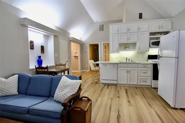 a living room with stainless steel appliances kitchen island granite countertop furniture and a wooden floor