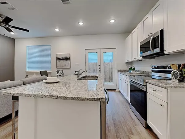 a kitchen with stainless steel appliances granite countertop a sink dishwasher a stove and a refrigerator with wooden floor