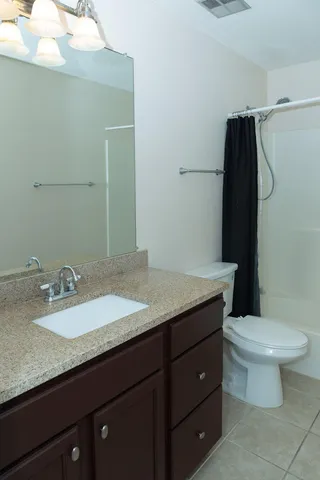 a bathroom with a granite countertop sink toilet and mirror
