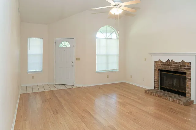 an empty room with windows and fireplace
